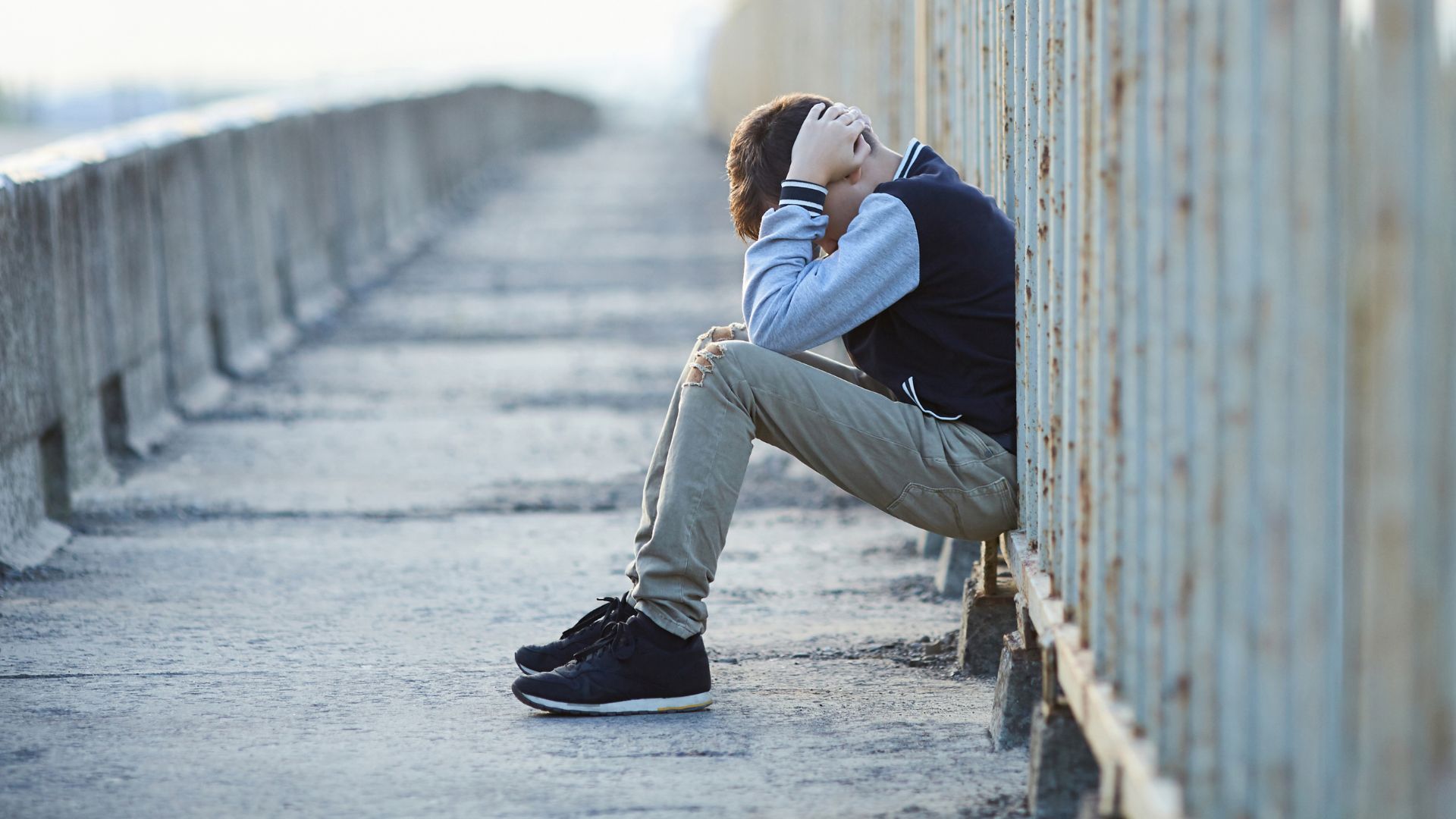 young homeless boy crying on the bridge